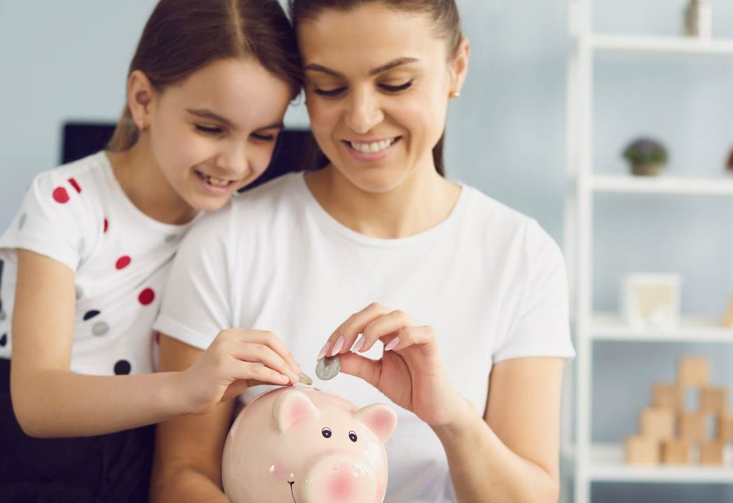 mom and daughter putting coins in bank