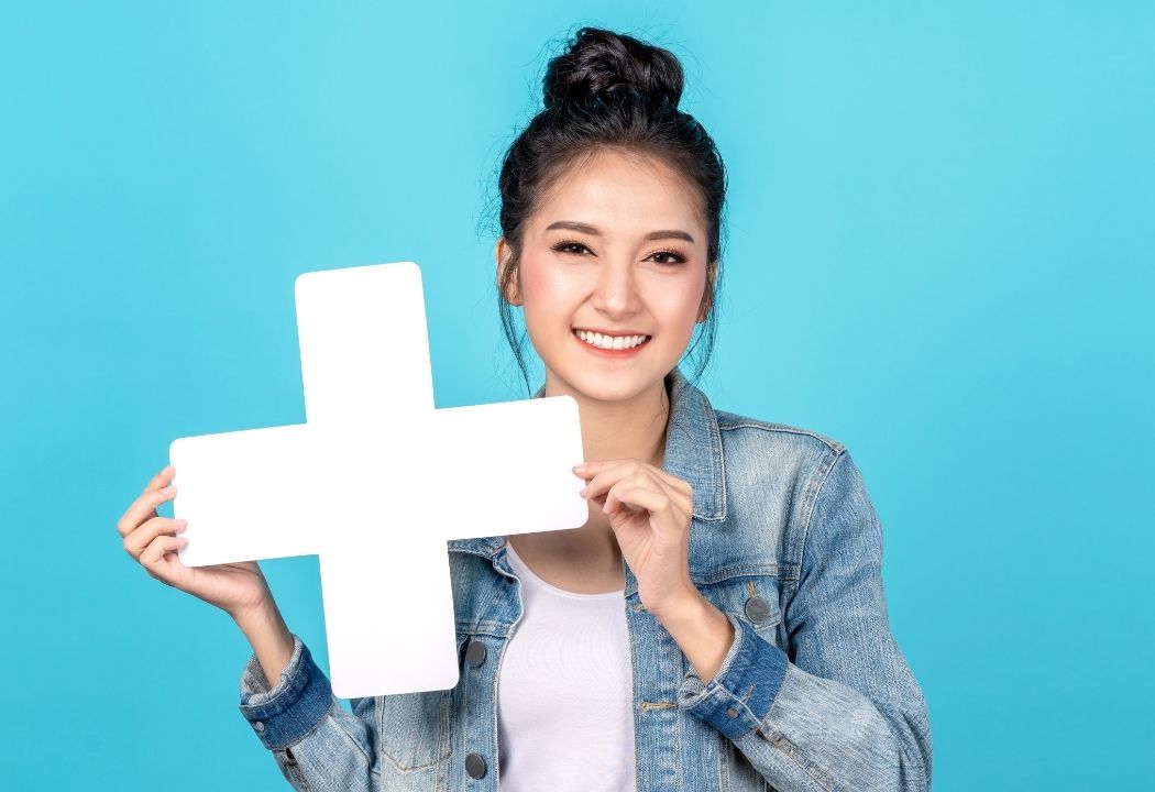 young Asian lady holding a plus sign