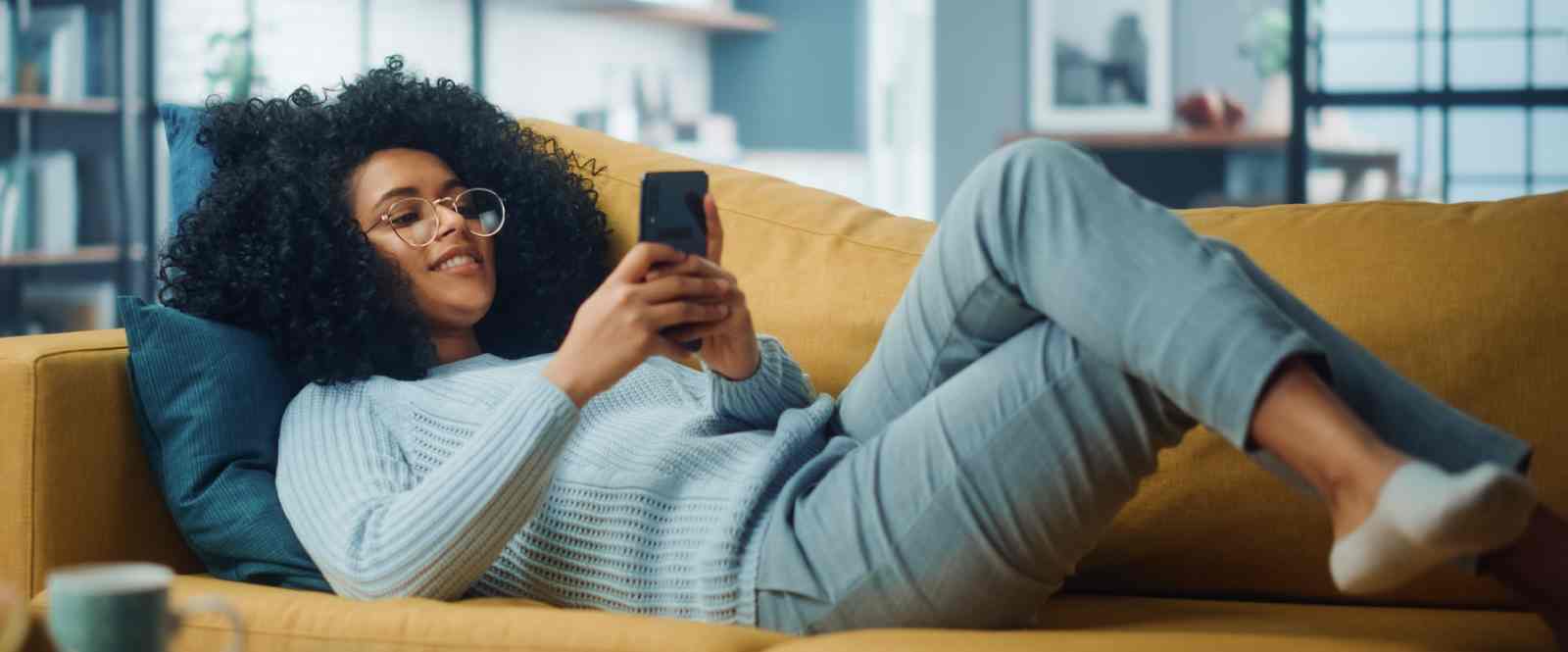 girl on phone laying on couch